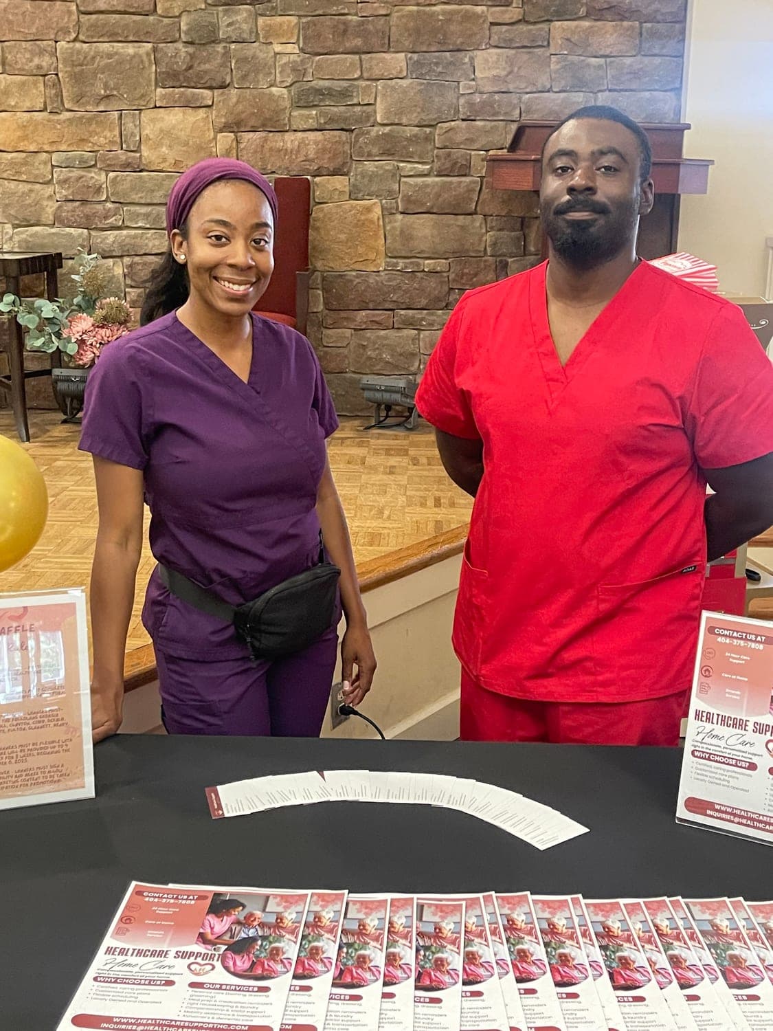 Two Healthcare Support team members in purple and red scrubs at the Pruitt Christian City Community Resource Event