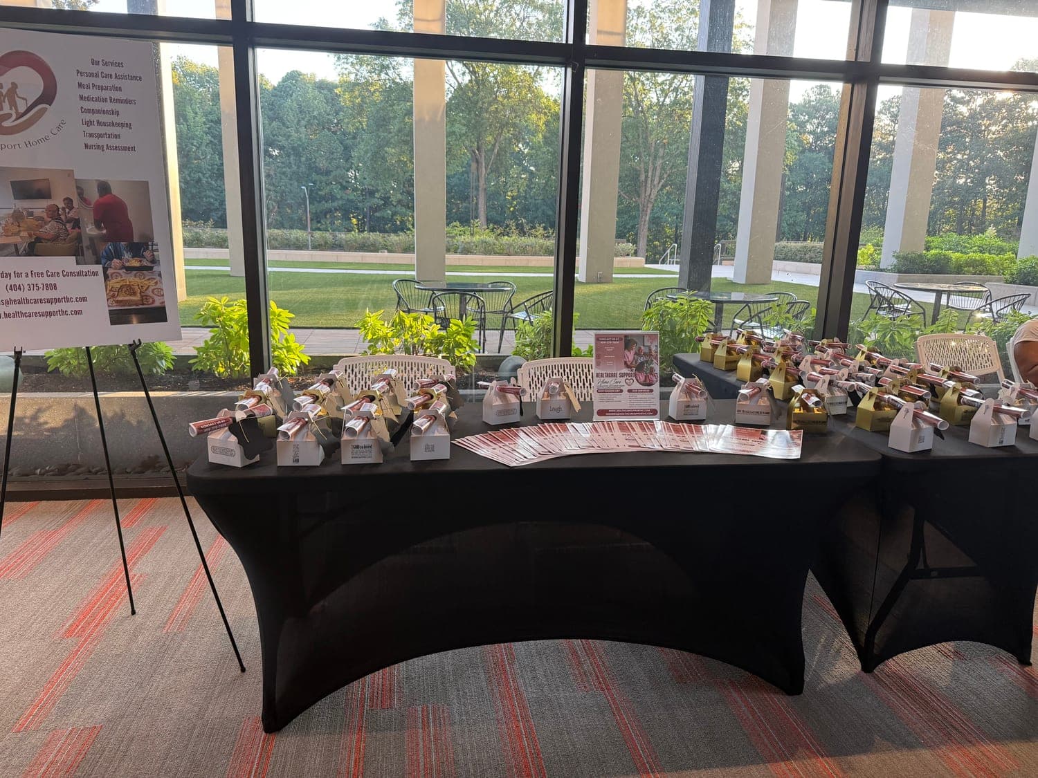 The Healthcare Support Home Care table at the WRISE Women's Conference 2025 with Rise Again Ministries in Buckhead, Atlanta, laid out with gift boxes beside tall windows