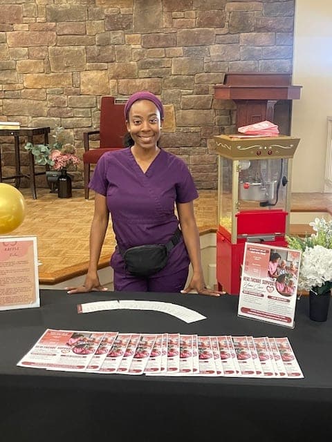 A Healthcare Support caregiver at the agency's table at a community event