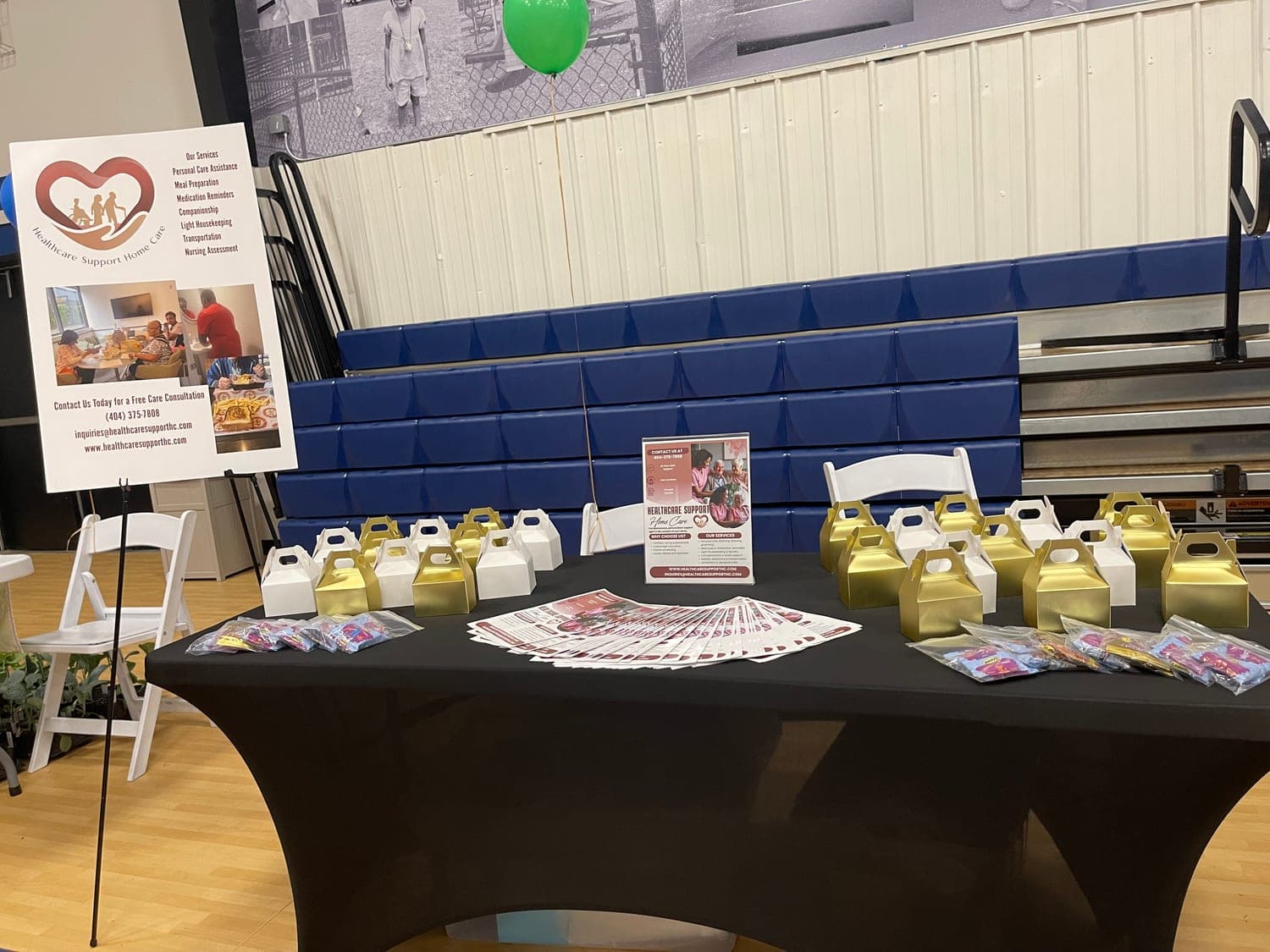 The Healthcare Support table at a community health fair, laid out with gift boxes and service flyers